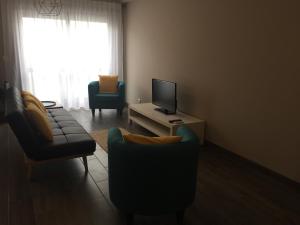 a living room with a couch and chairs and a television at The Lighthouse Apartment in Praia da Barra
