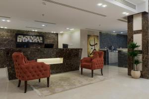 a lobby with two red chairs and a counter at Remaz Suites Hotel in Al Jubail