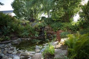 a garden with a pond and rocks and trees at Hotel Heiligenstein in Baden-Baden