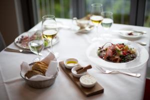a white table with a plate of food and glasses of wine at Hotel Heiligenstein in Baden-Baden