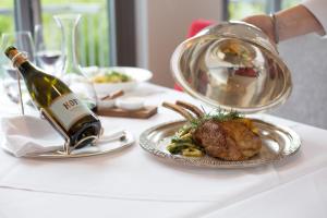 a table with a plate of food and a bottle of wine at Hotel Heiligenstein in Baden-Baden