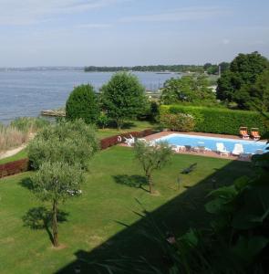 vista para uma piscina e para a água em Appartamento ORCHIDEA a Sirmione sul Lago di Garda con piscina, giardino e spiaggia con molo em Sirmione