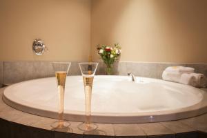 two champagne glasses sitting on a tub in a bathroom at Cornwall Motor Lodge in Palmerston North