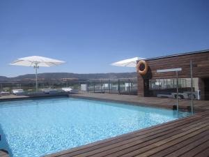a swimming pool with a wooden deck and a building at Sercotel El Encin Golf in Alcalá de Henares