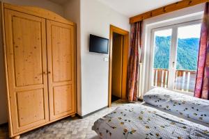 um quarto com uma cama e uma grande janela em Albergo Somont em Ortisei