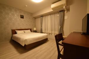 een slaapkamer met een bed, een bureau en een televisie bij Hotel Hakata Place in Fukuoka