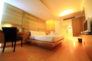 a bedroom with a bed and a chair and a television at Le Fenix Sukhumvit 11 Bangkok in Bangkok