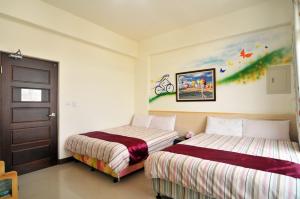 een slaapkamer met 2 bedden en een schilderij aan de muur bij Lin Yuan Bicycle Homestay in Taitung