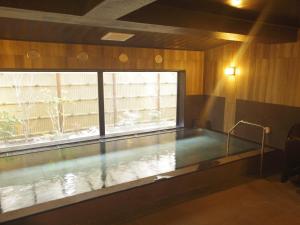a swimming pool in a room with a window at Hotel Route-Inn Kumamoto Ekimae in Kumamoto