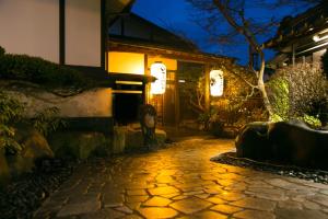 Una pasarela de piedra que conduce a una casa por la noche en Isamikan, en Nakagawa