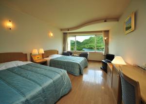 a hotel room with two beds and a window at Harunako Onsen Yusuge in Takasaki