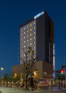 a hotel building with a tree in front of it at Sanco Inn Iseshi-Ekimae Shikinoyu in Ise