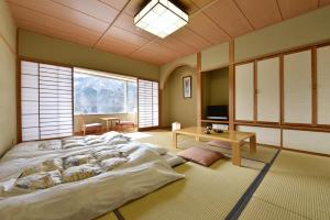 ein großes Bett in einem Zimmer mit einem großen Fenster in der Unterkunft Harunako Onsen Yusuge in Takasaki