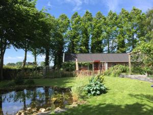 ein Haus mit einem Teich im Hof in der Unterkunft De Porrepoele in Alteveer