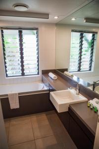 a bathroom with a tub and a sink and a mirror at 160 Temple Swimout Apt in Port Douglas