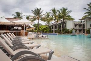 a pool with chaise lounge chairs next to a resort at 160 Temple Swimout Apt in Port Douglas