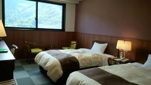 a hotel room with two beds and a window at Nezame Hotel in Agematsu