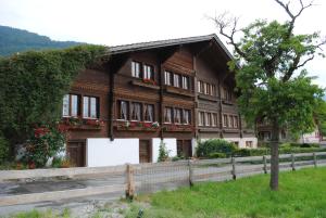 une maison en bois avec une clôture devant elle dans l'établissement Studio Glaus, à Wilderswil