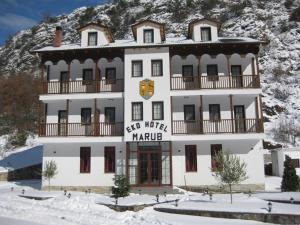 a large white building in front of a mountain at Hotel Marub in Rubik