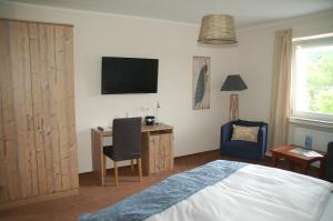 um quarto com uma cama, uma secretária e uma televisão em Hotel-Ferienwohnungen Cafe Maarblick em Schalkenmehren