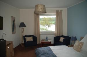 a bedroom with a bed and two chairs and a window at Hotel-Pension Maarblick in Schalkenmehren