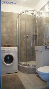 a bathroom with a shower and a washing machine at Studio Derdowskiego in Gdynia