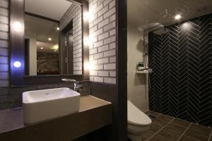 a bathroom with a sink and a toilet and a mirror at Hotel Chicago in Changwon