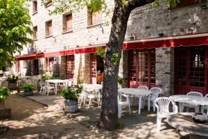 un groupe de tables et de chaises devant un bâtiment dans l'établissement Hôtel - Pub Le Petit Bosquet, à Santo-Pietro-di-Venaco