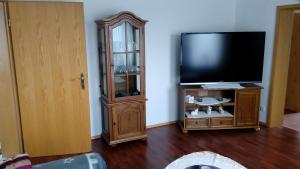 a living room with a flat screen tv and a cabinet at Ferienwohnung Stadie in Dörphof