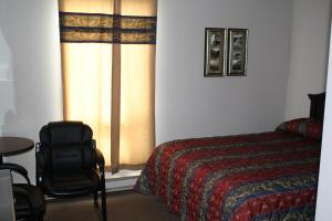um quarto com uma cama, uma cadeira e uma janela em The Country Inn Motel em Gander