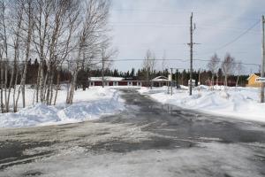 a street covered in snow with a house in the background at The Country Inn Motel in Gander