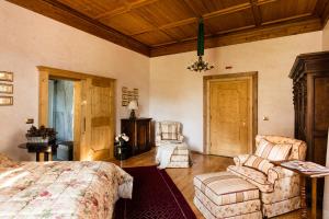 a bedroom with a bed and a couch and a chair at Schlosswirt Forst in Lagundo