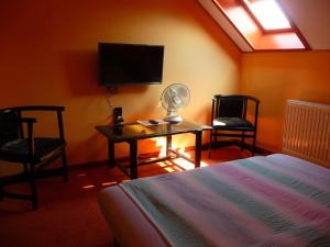 a bedroom with a bed and two chairs and a tv at Kőrös Hotel in Kiskőrös