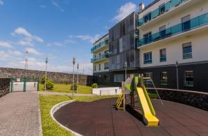 um parque infantil com um escorrega amarelo em frente a um edifício em Casa do Pico do Salomao em Ponta Delgada