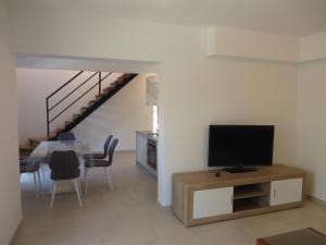 a living room with a television and a table with chairs at Luka Apartments in Biograd na Moru