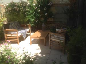 d'une terrasse avec une table, un lit et un banc. dans l'établissement Au Fond du Jardin Maison d'hôtes, à Saint-Saëns