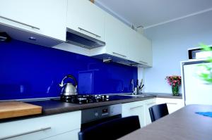 ソポトにあるVictus Apartamenty, Apartament Jantarの青い壁のキッチン(白いキャビネット付)