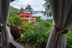 una finestra con tende e vista su una casa di Shivapuri Heights Cottage a Kathmandu Altre 37 foto