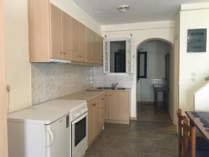 a kitchen with wooden cabinets and a white stove top oven at Serifos Palace in Livadakia