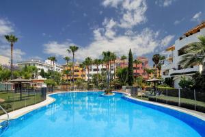 マルベーリャにあるLuxury Apartment In Marbellaのヤシの木と建物が並ぶリゾートのスイミングプールを利用できます。