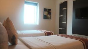 Hotel Jolin في ماكاسار: غرفة بسريرين ونافذة وتلفزيون