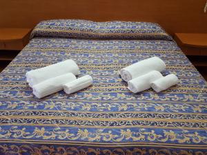 3 rollos de papel higiénico sentados en una cama en Hotel Saponi en Rímini