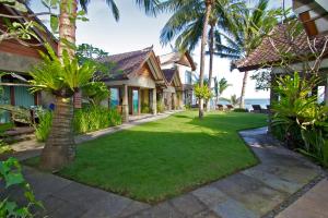 a yard with palm trees and a house at Bayshore Villa in Candidasa