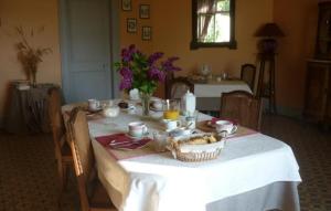 einen Tisch mit einem weißen Tischtuch und einem Korb mit Lebensmitteln in der Unterkunft Le Clos des ifs in Thiétreville