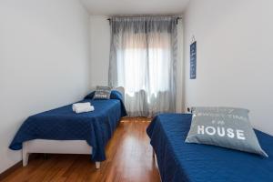 Habitación con 2 camas con sábanas azules y ventana en Ortaglia, en Torri del Benaco