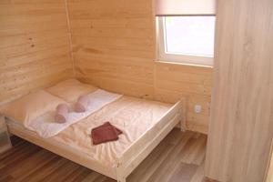 a small bed in a wooden room with a window at Domki Letniskowe u Susła in Sianozety