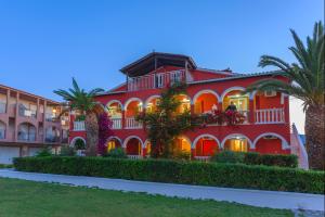 un edificio rojo con palmeras delante en Tropical Studios en Laganas