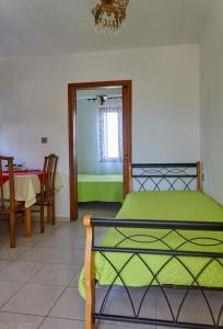 Dimitra Apartments في سيتيا: غرفة نوم بسرير اخضر وطاولة