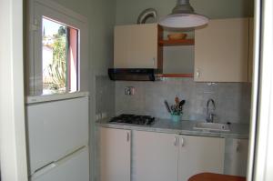 a kitchen with white cabinets and a sink and a window at Solanha monolocale n.4 in Cavo