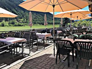 a restaurant with tables and chairs with umbrellas at Hotel Pizzeria Selva in Zernez